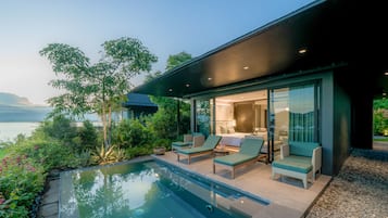 Una casa moderna con piscina, mobiliario exterior y vista al agua.