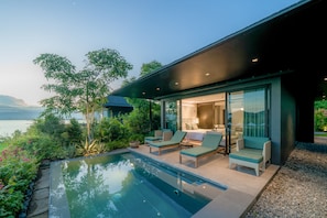 Et moderne hus med swimmingpool, udendørs møbler og udsigt til vandet.