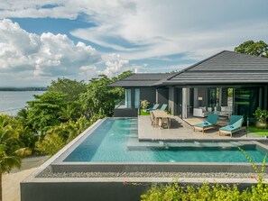 Ein modernes Haus mit Pool, Sitzgelegenheiten im Freien und Meerblick.