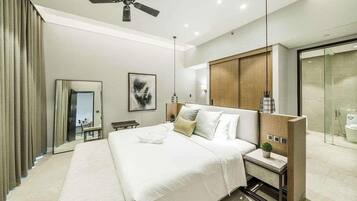 A modern hotel room with a large bed, a bedside table with a lamp, a mirror, and a view of the bathroom.