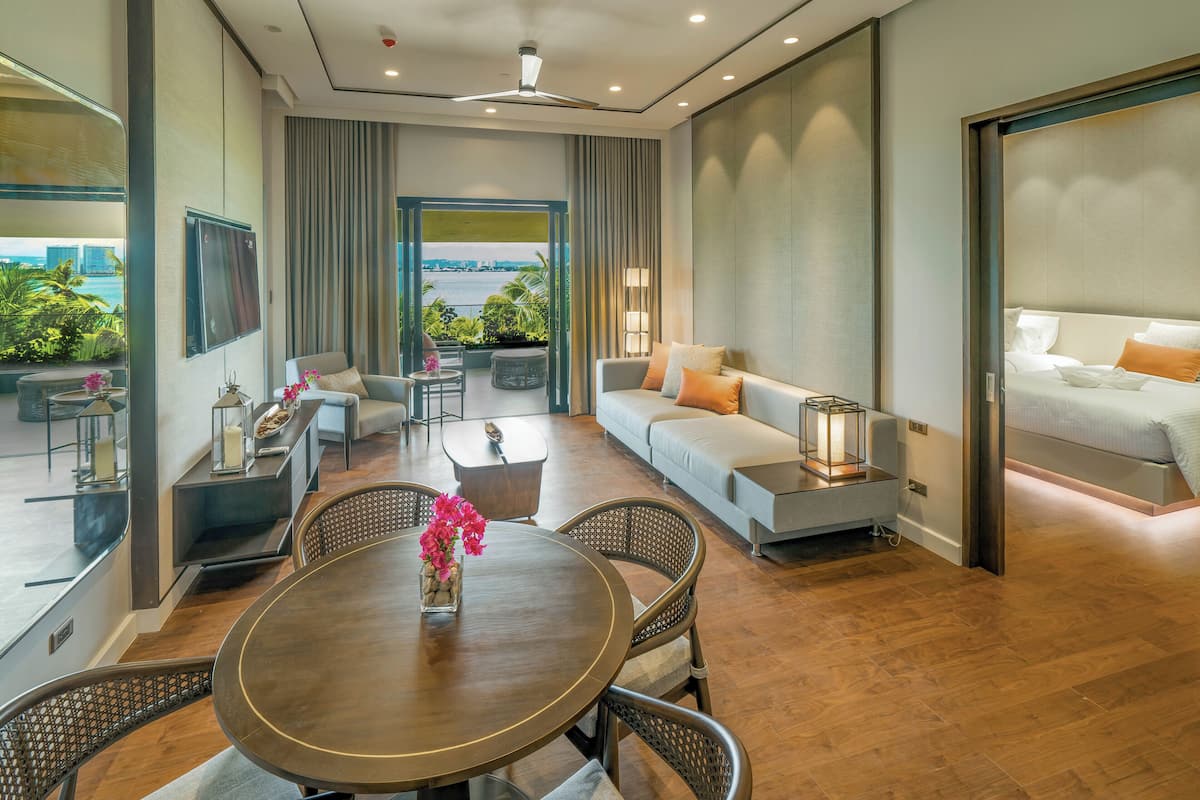 Quarto de hotel moderno com varanda, sofá, mesa de jantar e cama.