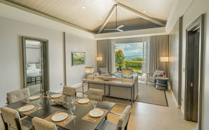 A modern dining area with a large table set for six, a ceiling fan, and a view of the outdoors.