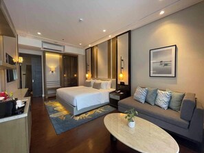 Une chambre d’hôtel moderne, équipée d’un lit, d’un canapé, d’une table basse et d’un grand miroir.