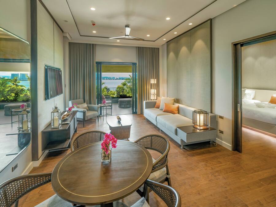 Una habitación de hotel moderna con balcón, sofá, mesa de comedor y cama.