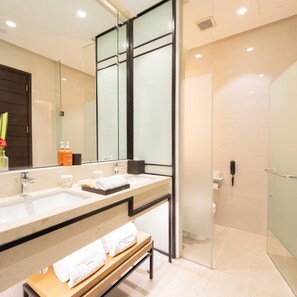 Un baño moderno con tocador doble, cabina de ducha con mampara de vidrio y un banco con toallas.