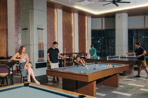 A pool area with multiple tables and chairs, a billiards table, and a ping pong table.