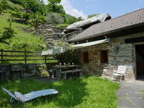 Guests can relax in the peaceful seating area, surrounded by lush greenery and a wooden fence.