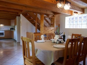 Enjoy meals in this cozy dining area with a wooden table set for four, surrounded by matching chairs and exposed beams.