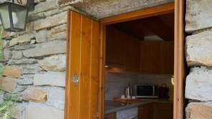 A stone wall exterior with a wooden door leading to a kitchen area. - Rustico Cleo by Interhome (Semione)