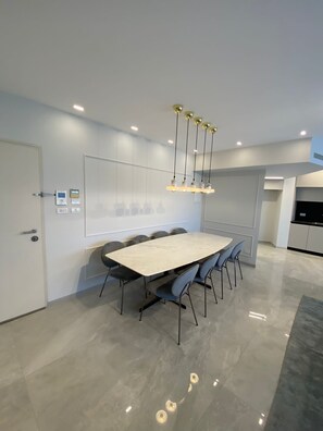 A modern dining area with a rectangular table, six chairs, and a pendant light fixture.