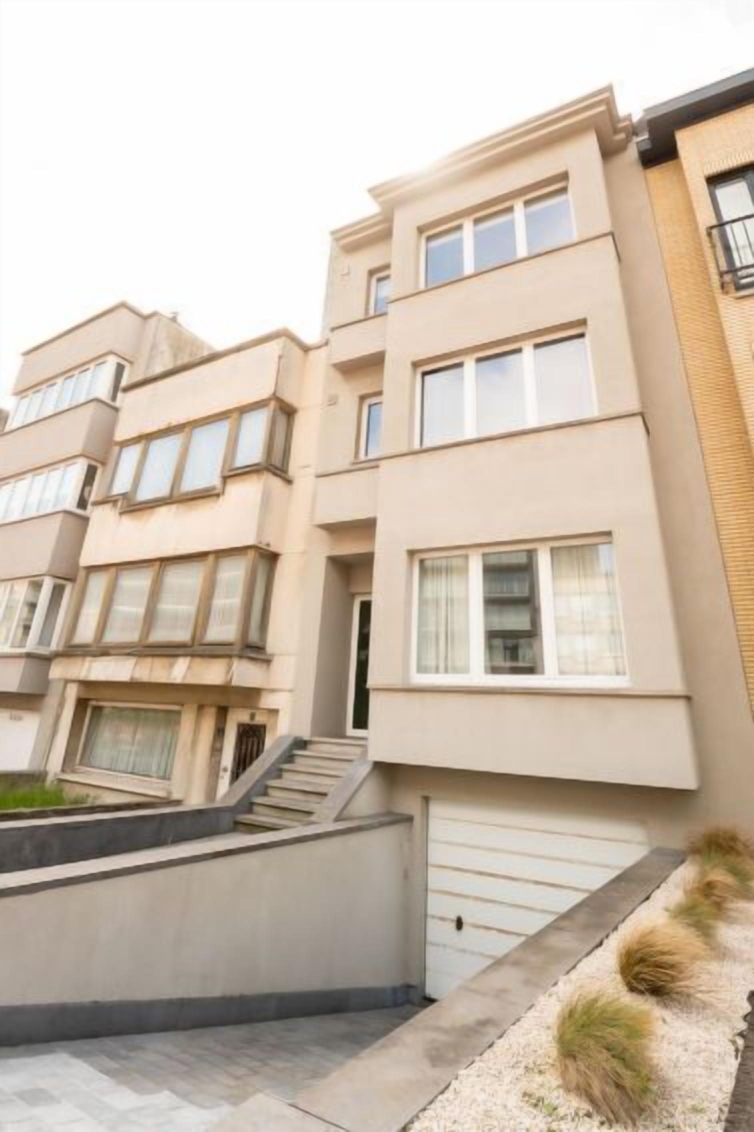 A multi-story residential building with a flat facade, large windows, and a visible garage door.