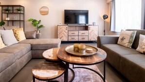 A modern living room with a sectional sofa, a round coffee table, and a TV on a wooden cabinet. - Philemon with parking by Interhome (Blankenberge)