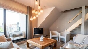 Un salon moderne avec une table basse en bois, des canapés gris et un téléviseur posé sur un meuble.