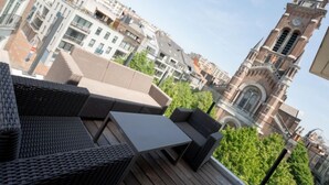 Une terrasse sur le toit, aménagée avec des meubles en osier et offrant une vue sur une tour historique.