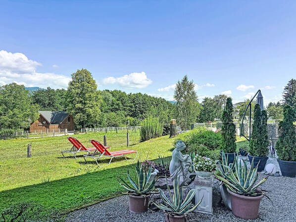 A garden with red lounge chairs, a statue, and potted plants.