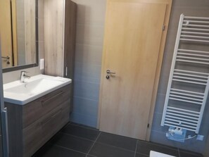 A bathroom with a white sink, wooden vanity, a door, and a towel rack. - Löwenzahn by Interhome (Velden am Wörthersee)