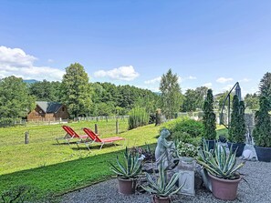 A garden with red lounge chairs, a statue, and potted plants.