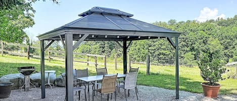 Ein Gazebo mit Metallveranda und Kiesboden, umgeben von Stühlen und einem Tisch.