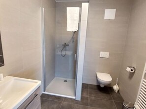 A modern bathroom with a glass-enclosed shower, a toilet, and a sink. - Apartment Lilie by Interhome (Velden am Wörthersee)