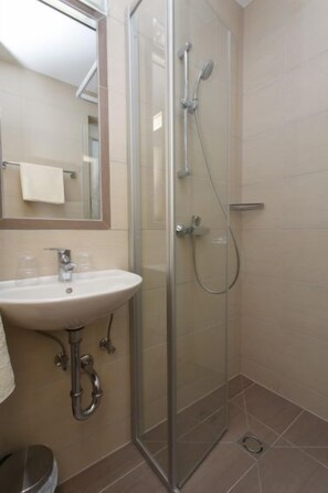 Ein Badezimmer mit Duschkabine, Waschbecken und Spiegel.