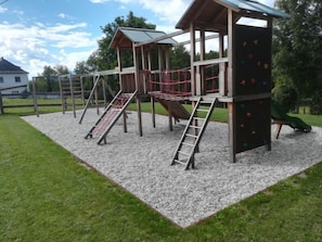 Ein Spielplatz mit verschiedenen Klettergerüsten, Rutschen und einem überdachten Spielbereich.