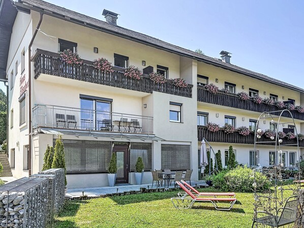 A multi-story hotel with balconies, outdoor seating, and a well-maintained garden.