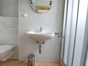A bathroom with a white sink, a toilet, and a trash bin. - Mohnblume by Interhome (Velden am Wörthersee)