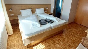 Una cama doble con cabecera de madera, dos almohadas y toallas dobladas sobre la cama.