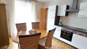 Una cocina compacta con una mesa y sillas, una cafetera y una estufa.