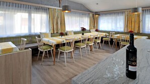 Un comedor con mesas y sillas de madera, una botella de vino y una encimera de mármol.
