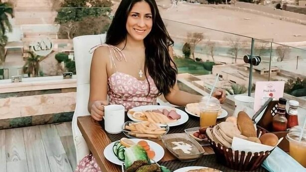 Una mesa de comedor con comida y bebidas, una vista de pirámides y un paisaje urbano al fondo.