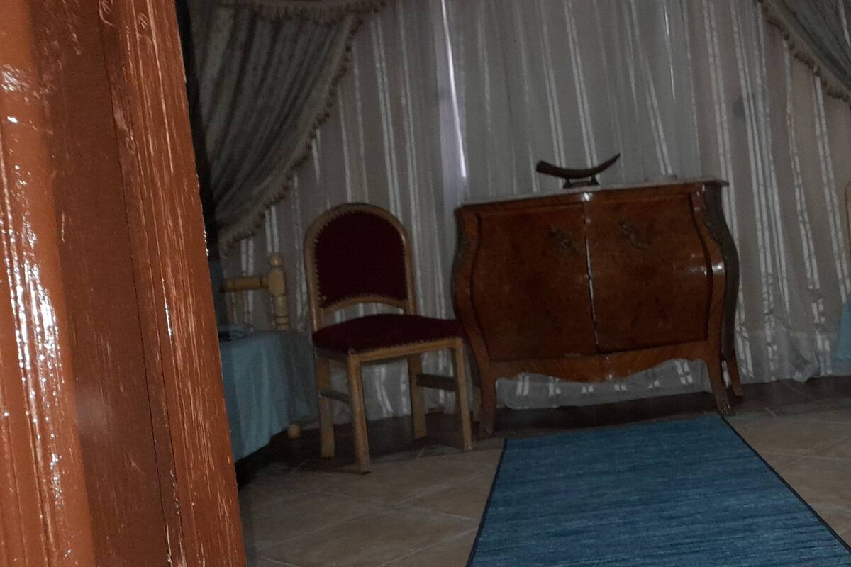 Une pièce comprenant un lit, une commode en bois, une chaise et un tapis bleu.