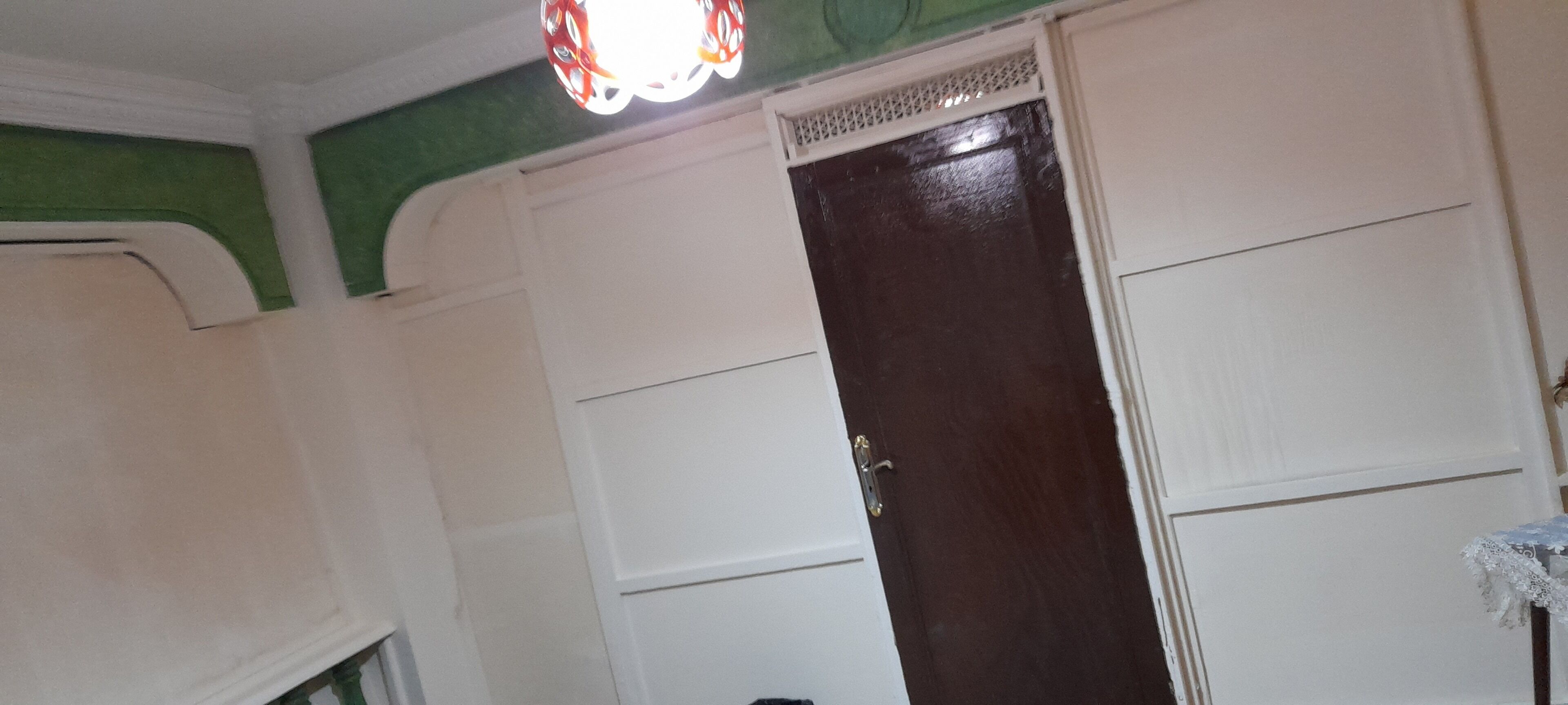A room with a closed dark wooden door, white walls, and a green accent wall.