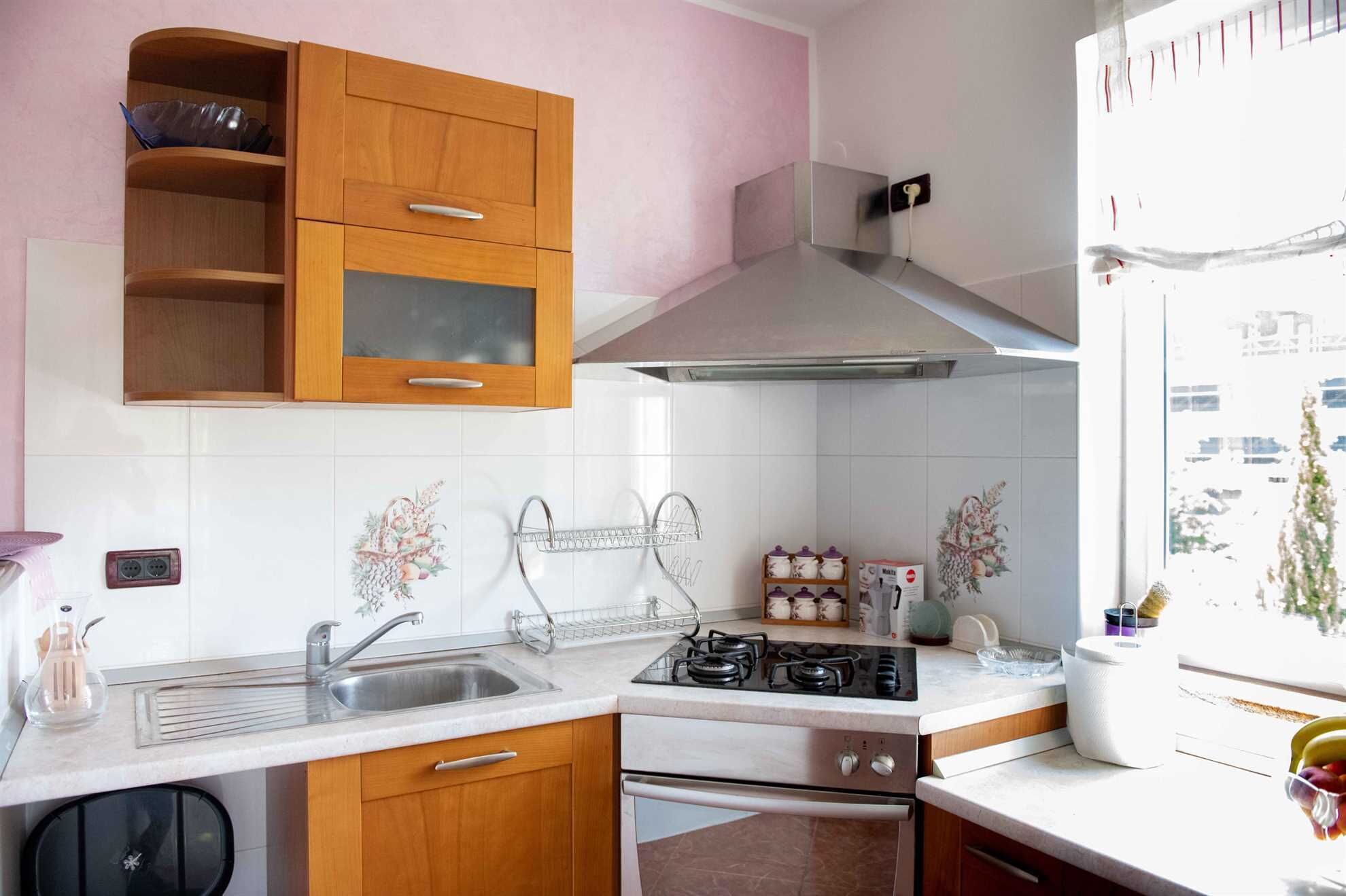 Una cocina con armarios de madera, un lavamanos de acero inoxidable, una estufa a gas y una ventana con vistas.