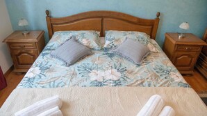 A bed with floral bedding, two pillows, two bedside tables with lamps, and towels on the bed. - KATA Two-Bedroom Apartment with Balcony (Rovinj)