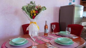 Ein Esstisch gedeckt mit grünen Tellern, Weingläsern und einem Blumenstrauß in einer weißen Vase.