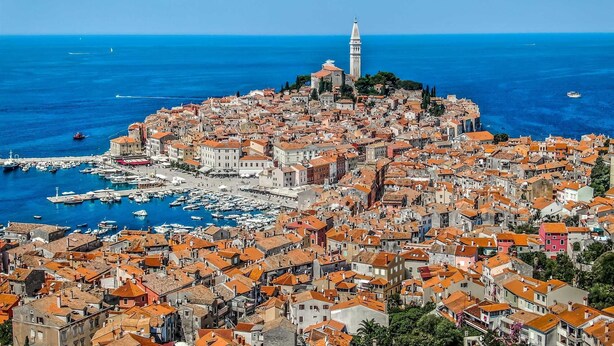A coastal town with a prominent tower, dense buildings with red-tiled roofs, and a marina with boats. - KATA Two-Bedroom Apartment with Balcony (Rovinj)
