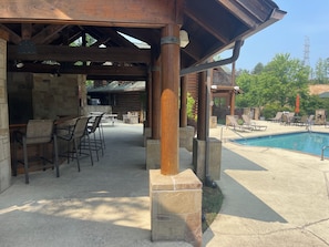 Un patio couvert avec des murs en pierre, des sièges d’extérieur et un espace piscine.