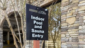 A sign for an indoor pool and sauna entry at a building with stone walls and a large window. - 3 minutes to Dollywood Entrance. Fall Discounts 2bd 2ba Condo.  (Pigeon Forge)