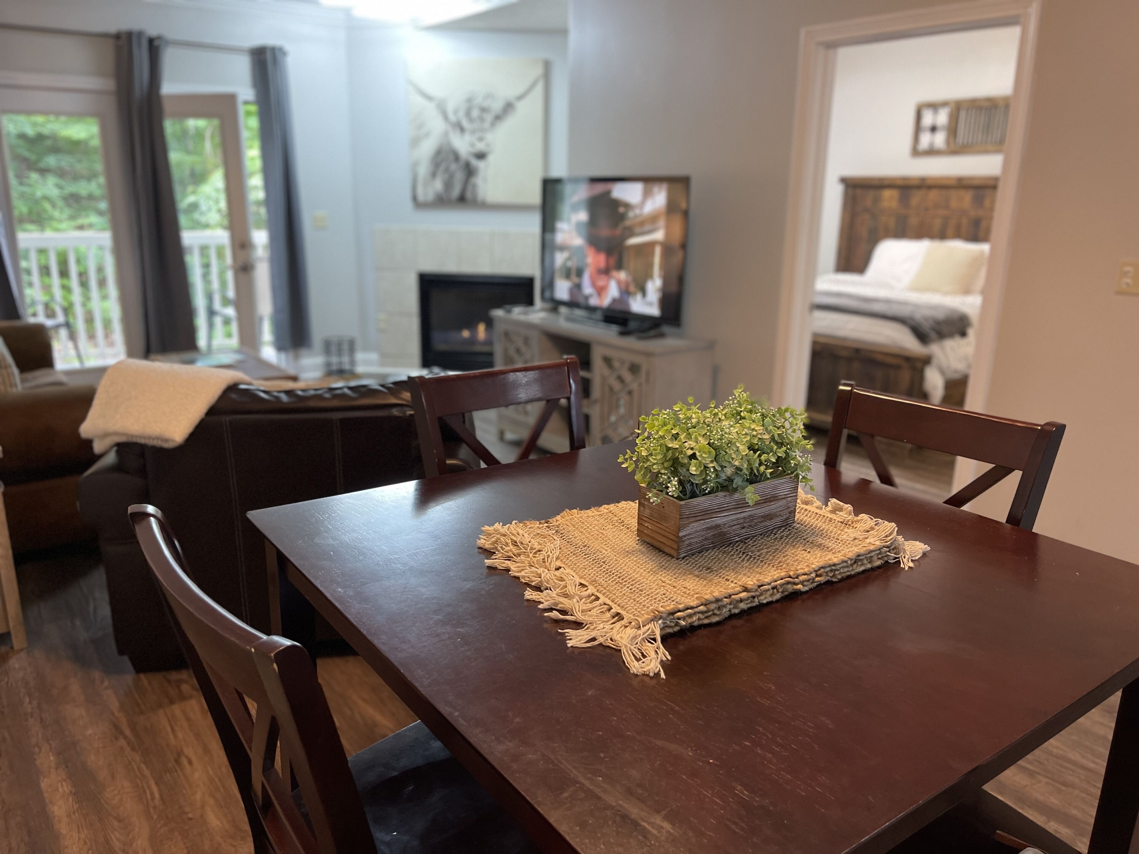 A dining area with a wooden table, chairs, and a small plant centerpiece.