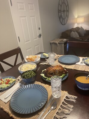 Una mesa de comedor dispuesta con diferentes platos, incluyendo un pavo asado, judías verdes y una ensalada.