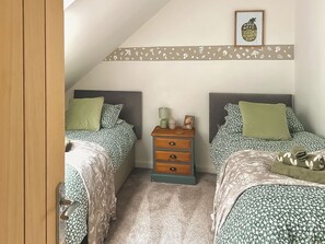Une chambre avec deux lits, une table de chevet, un tableau encadré et une bordure décorative sur le mur.