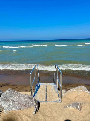 A beach with a wooden staircase leading to the water, surrounded by large rocks.