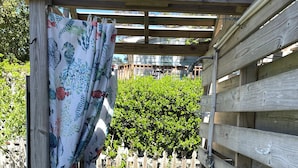 Una pergola in legno con un recinto in legno bianco, una panchina di legno e un vialetto che conduce a un arbusto verde.