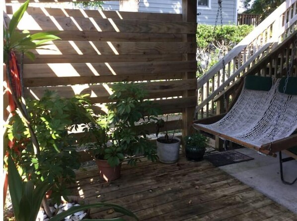 A wooden deck with a hammock, potted plants, and a staircase. - Lost in Lost Colony (Nags Head)