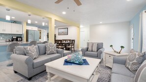 A modern living room with a pool, grey sofas, a white coffee table, and a ceiling fan. - Beach Getaway on Cocoa Beach (Cocoa Beach)