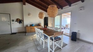 Una cocina amplia con una mesa de madera y sillas blancas, un armario de madera y un ventanal grande.