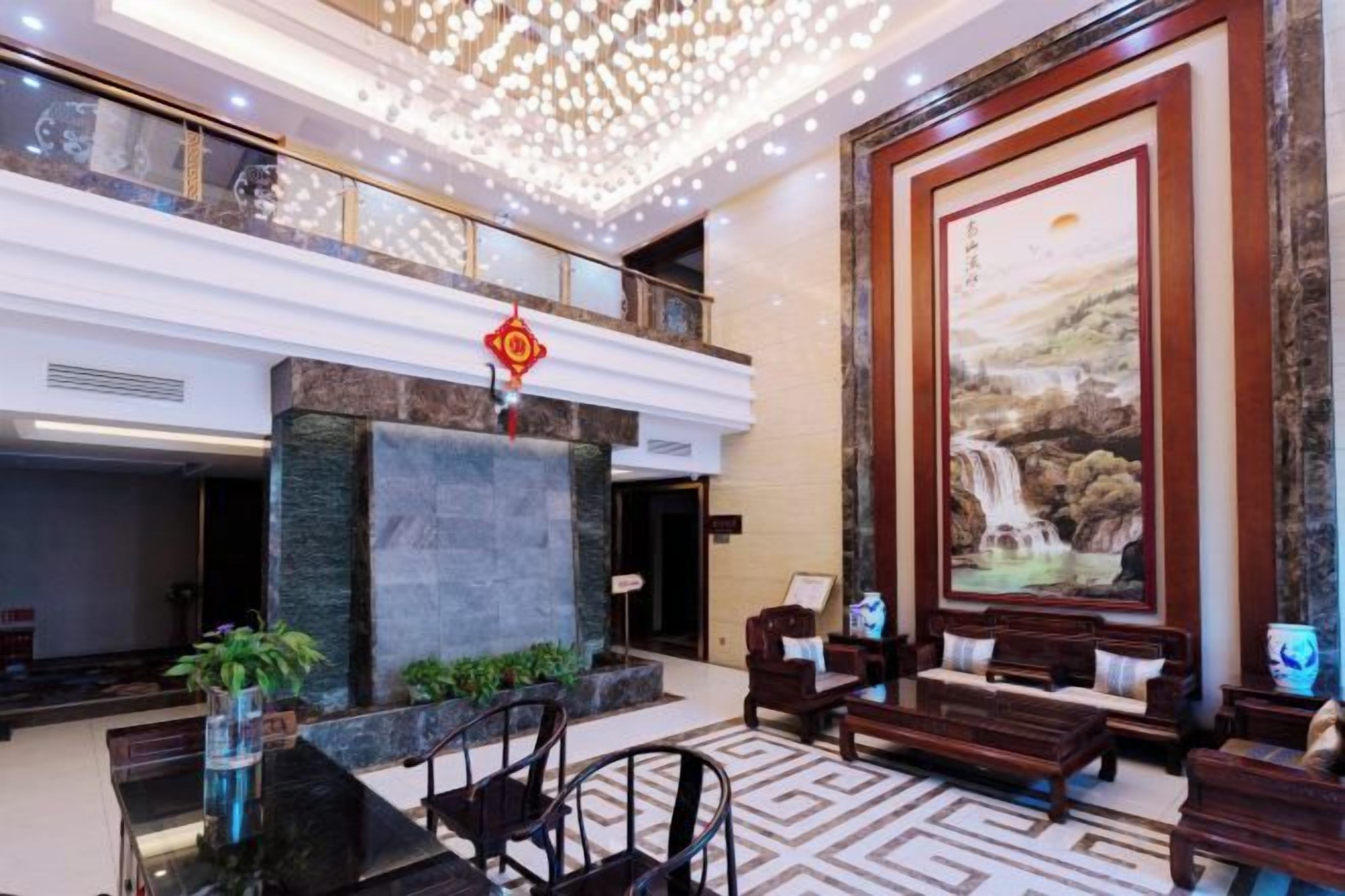 A lobby with a reception desk, seating area, and a large painting.