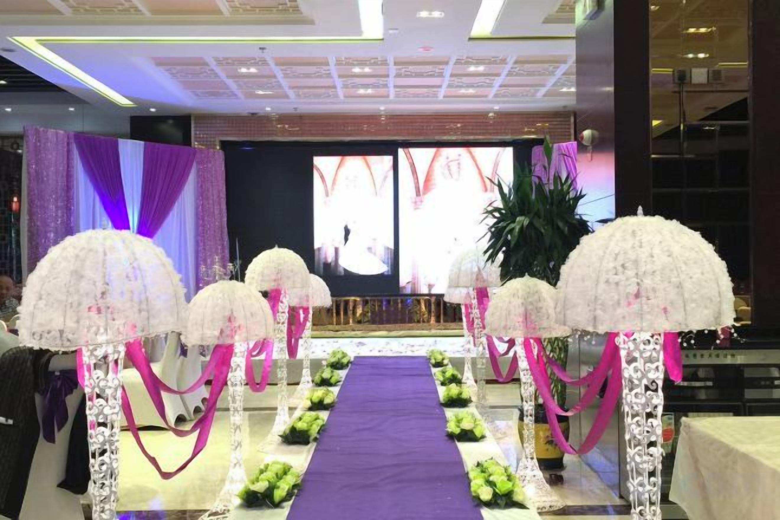 A stage with a purple carpet and white floral arrangements.