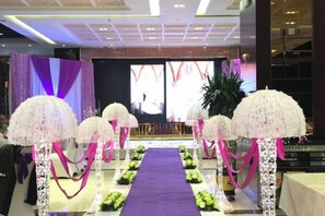 Un escenari amb una catifa morada i composicions florals blanques.